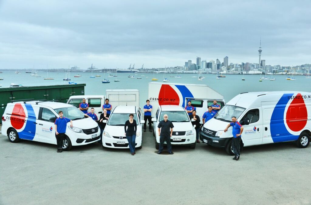 Staff and vehicles lined up in front of Auckland skyline, showing company commitment to reliable decontamination services